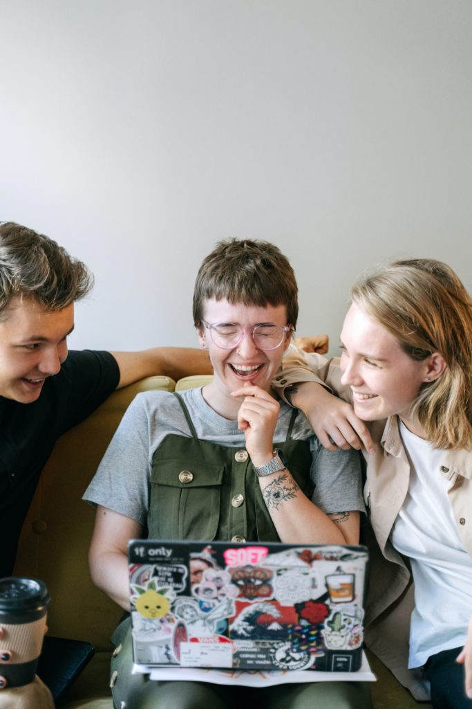 3 Teammitglieder lachen gemeinsam vor einem Laptop