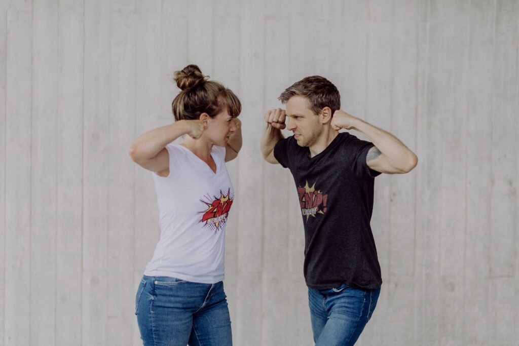 Henry Schneider und Janina Kappelhoff stehen sich mit einer Kraft-Pose Gegenüber