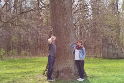 Henry und Janina nehmen Haltung an vor einem großen Baum